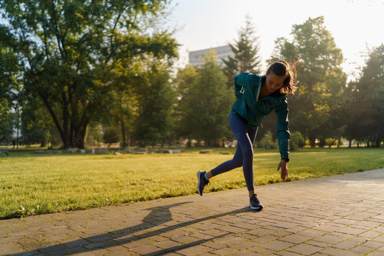 Full lenght portrait of beautiful fitness woman doing running drills in the city park. Workout at the park. Outdoor workout concept.