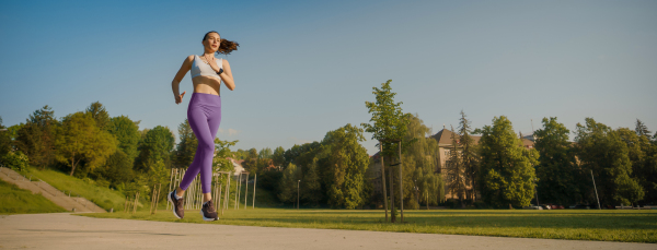 portrait of athletic young woman in activewear running in the city in the morning. Outdoor workout concept. Banner with copy space.