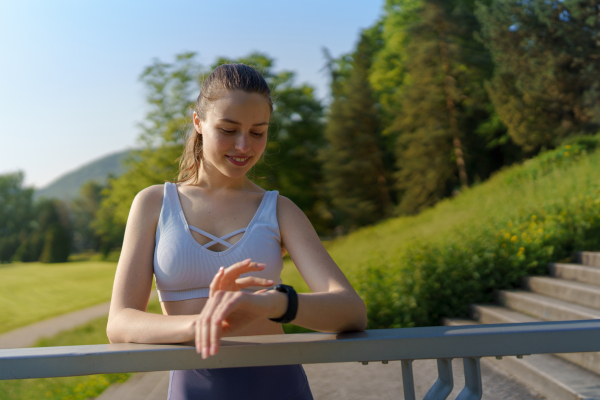 Potrait of sporty woman checking her performance on smartwach after workout session. Woman using smartwatch to sending text message, calling.