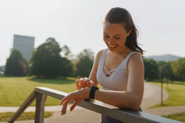 Sporty woman checking her performance on smartwach after workout session. Woman using smartwatch to sending text message, calling.