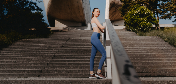 Portrait of sporty woman running on the concrete stairs in city park. Female athlete in sportswear doing stair workout outside. Healty lifestyle concept. Banner with copyspace.