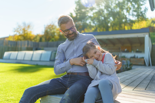 Father with his little daughter on their backyard during a sunny autumn day.