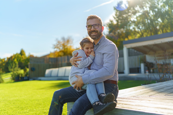 Father with his little daughter on their backyard during a sunny autumn day.