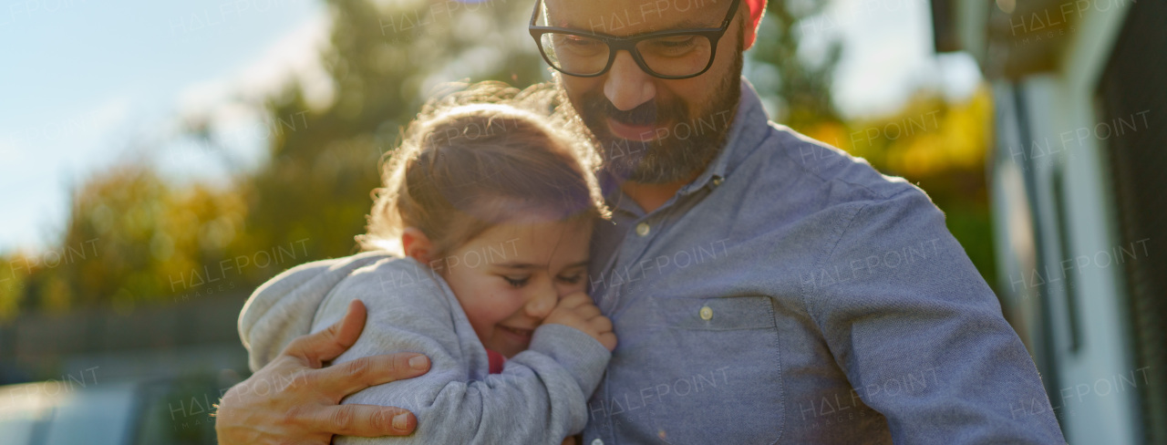 Father with his little daughter on their backyard during a sunny autumn day.