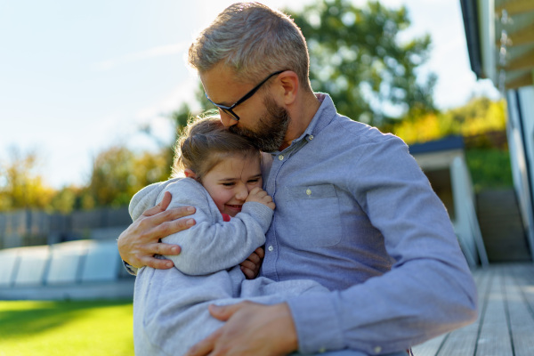 Father with his little daughter on their backyard during a sunny autumn day.