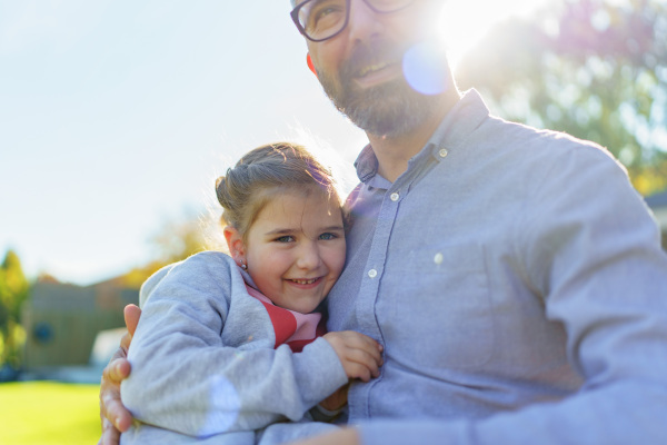 Father with his little daughter on their backyard during a sunny autumn day.