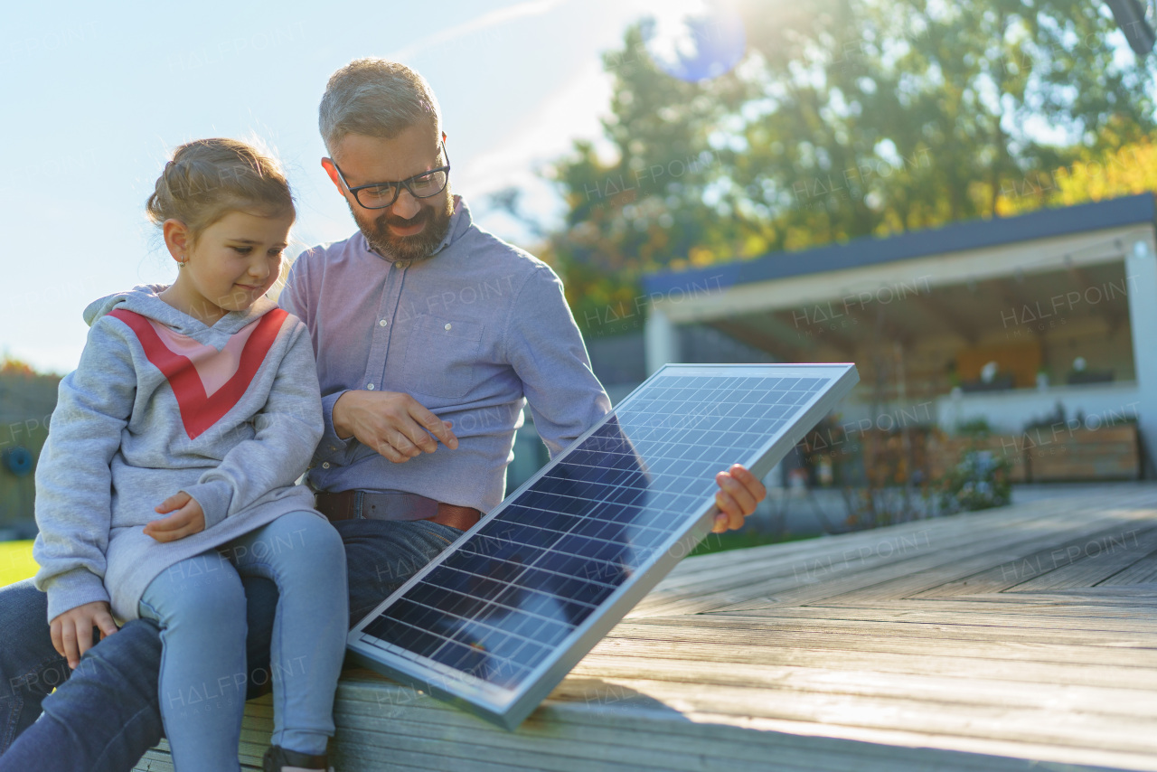 Father showing his little daughter a solar photovoltaics panels, explaining how it works. Alternative energy, saving resources and sustainable lifestyle concept.