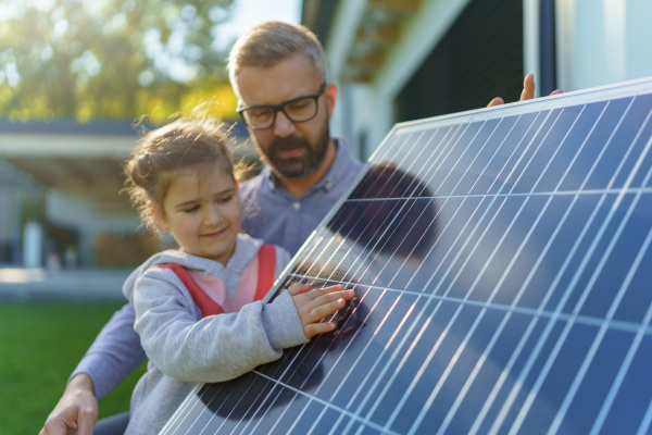 Father showing his little daughter solar photovoltaics panels, explaining how it working. Alternative energy, saving resources and sustainable lifestyle concept.