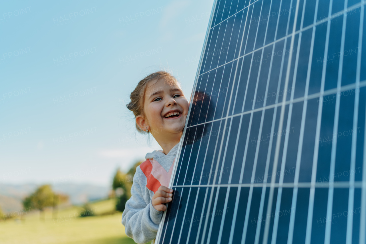 Little girl holding a photovoltaics solar panel. Alternative energy, saving resources and sustainable lifestyle concept.