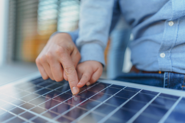 Close-up of father showing his little daughter a solar photovoltaics panels, explaining how it works. Alternative energy, saving resources and sustainable lifestyle concept.