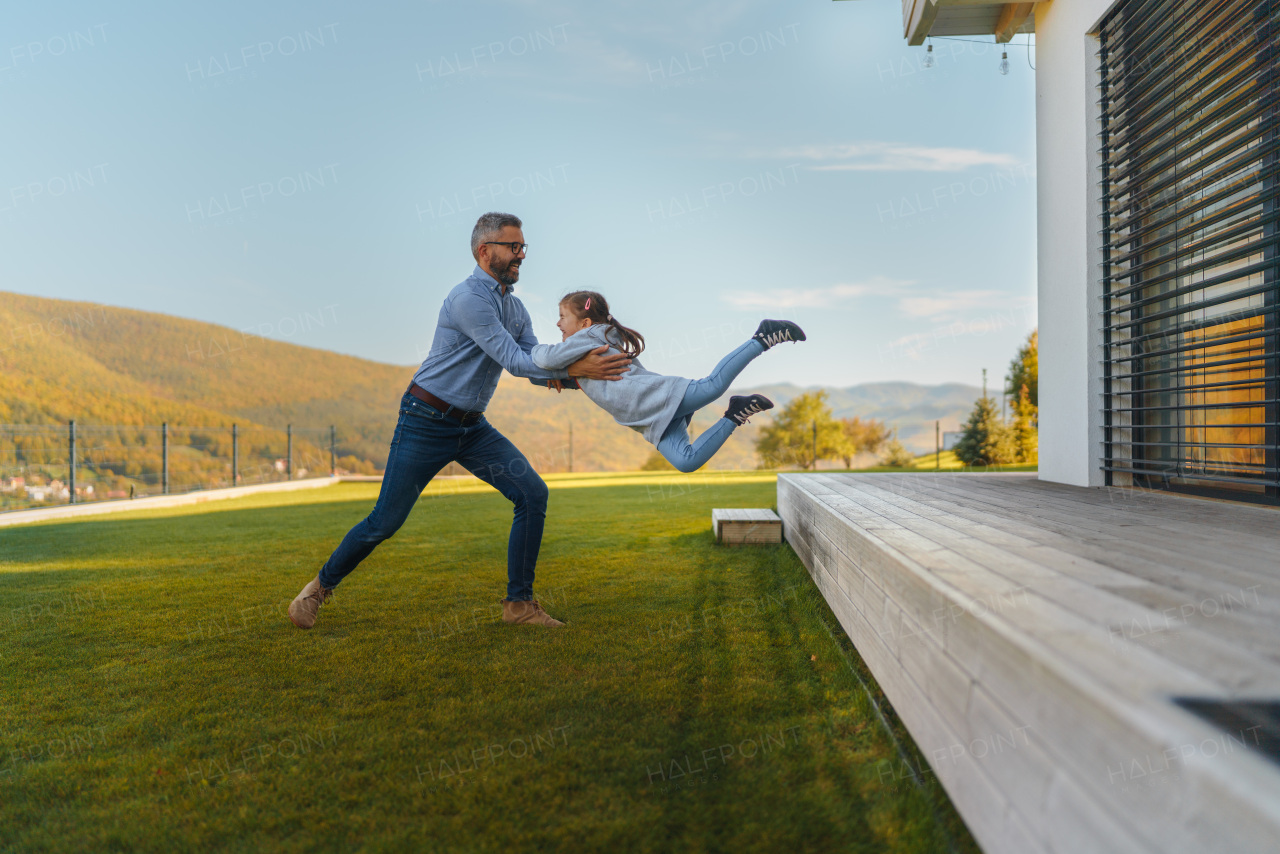 Father with his little daughter having fun in their backyard during a sunny autumn day.