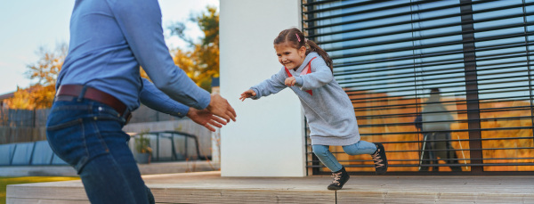 Father with his little daughter having fun in their backyard during a sunny autumn day.