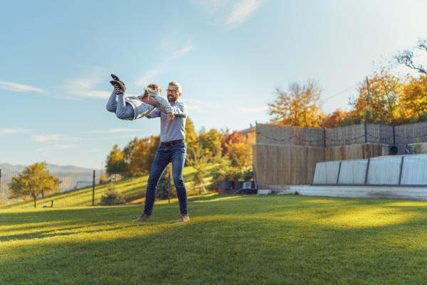 Father with his little daughter having fun in their backyard during a sunny autumn day.