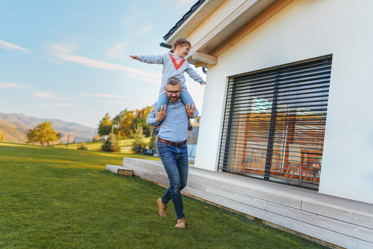 Father with his little daughter having fun in their backyard during a sunny autumn day.