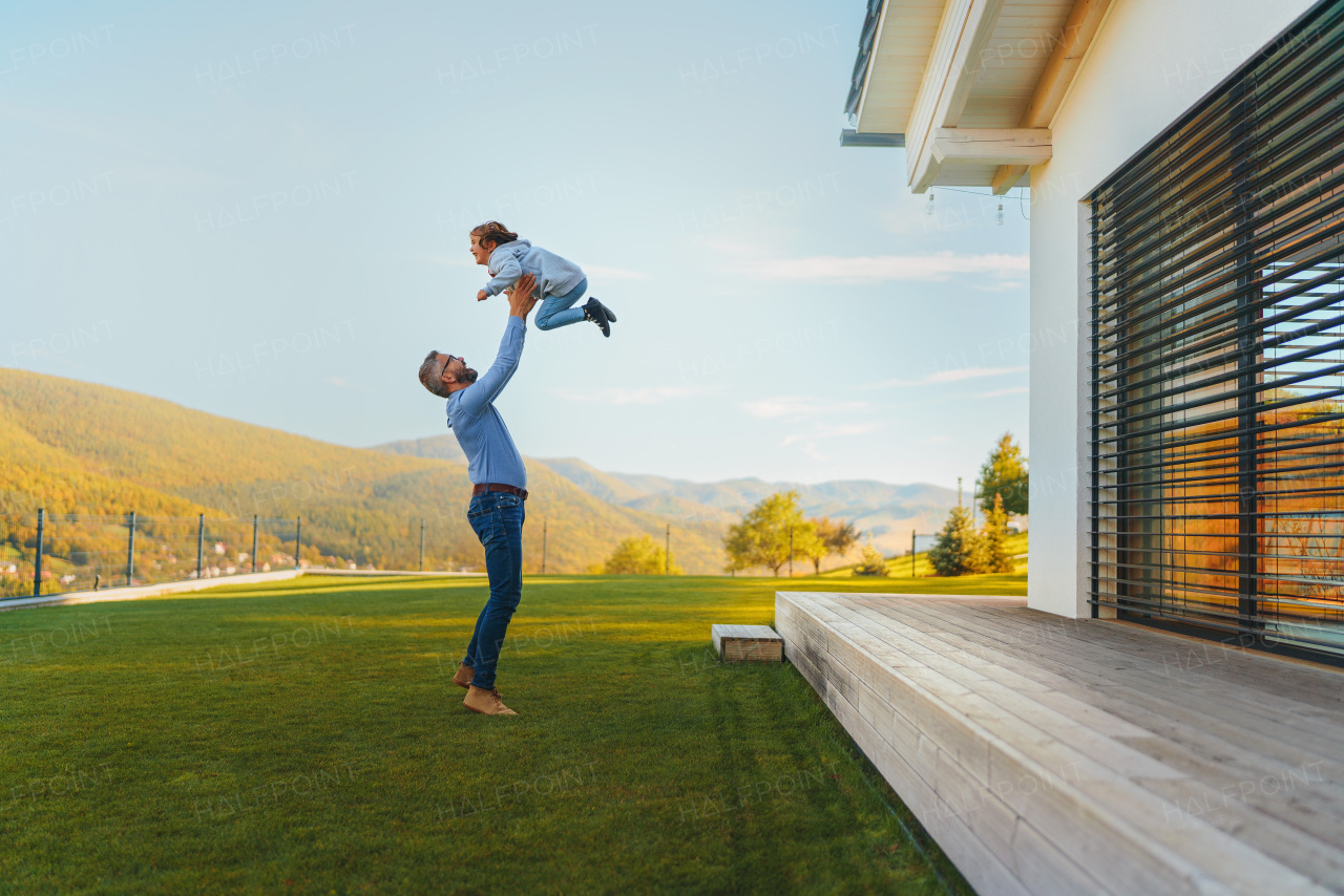 Father with his little daughter having fun in their backyard during a sunny autumn day.