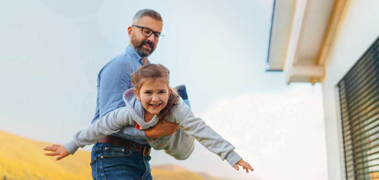 Father with his little daughter having fun in their backyard during a sunny autumn day.