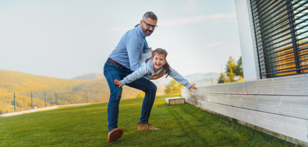 Father with his little daughter having fun in their backyard during a sunny autumn day.