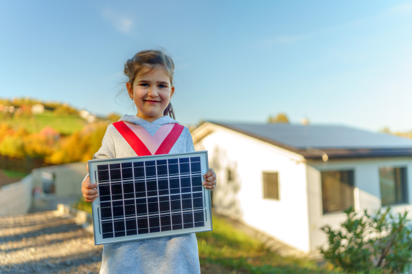 Little girl holding a photovoltaics solar panel. Alternative energy, saving resources and sustainable lifestyle concept.