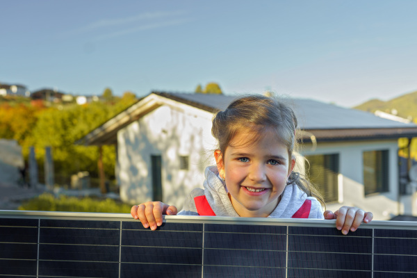 Little girl holding a photovoltaics solar panel. Alternative energy, saving resources and sustainable lifestyle concept.