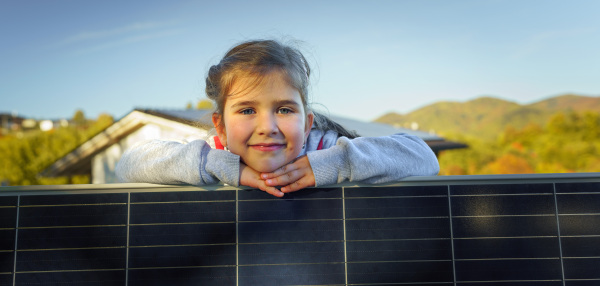 Little girl with a photovoltaics solar panel. Alternative energy, saving resources and sustainable lifestyle concept.