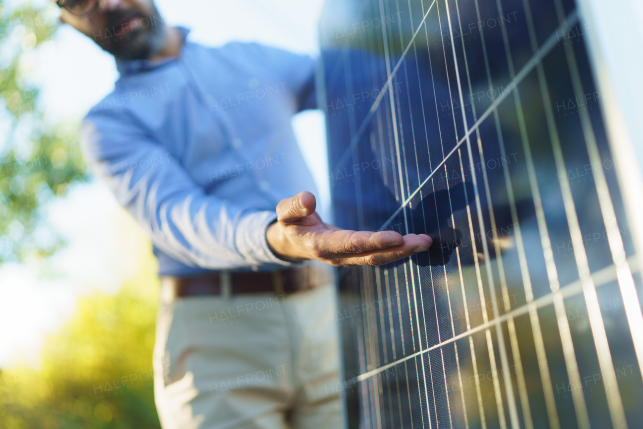 Businessman holding and explaining how solar panel works, standing outdoor at a garden.