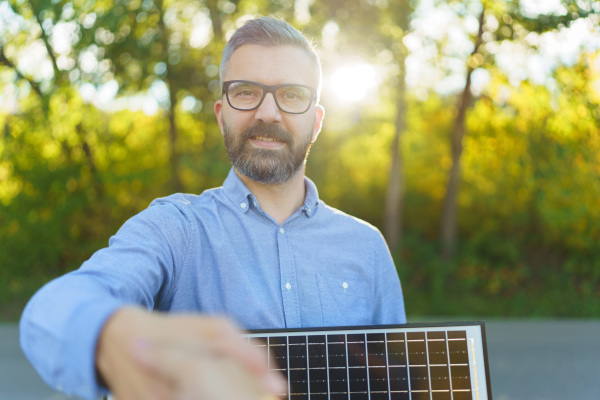 Businessman holding selling solar panel,shaking hand with a customer.