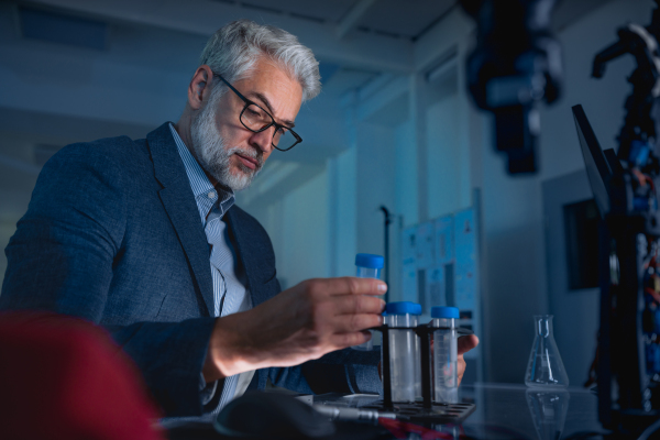 Male scientist in the laboratory holding test tubes and intently looking at its contents.