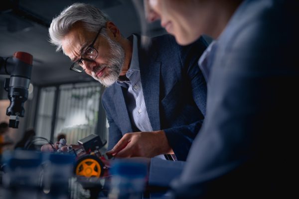 Two robotics engineers working on new project, standing in laboratory. Concept of modern technology in industries, automated processes, automotive.