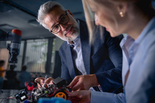 Two robotics engineers assembling robotic car. Concept of modern technology in industries, automated processes, automotive.