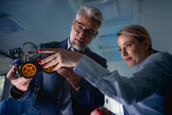 Two robotics engineers assembling robotic car. Concept of modern technology in industries, automated processes, automotive.