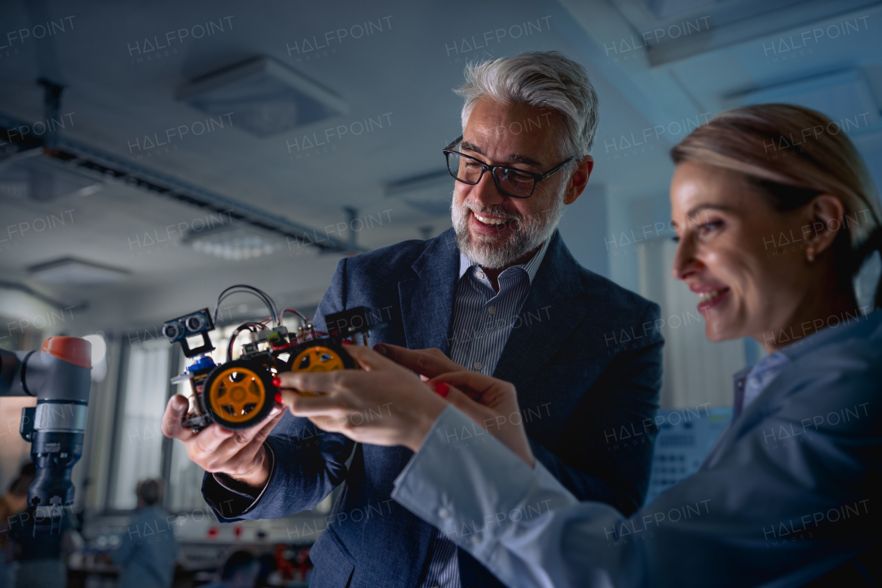 Two robotics engineers working on new project, standing in laboratory. Concept of modern technology in industries, automated processes, automotive.