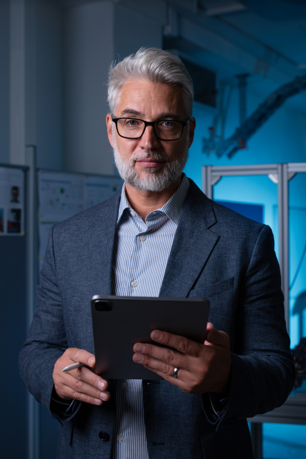 Portrait of robotics engineer holding tablet, looking at camera. Concept of modern technology in industries, automated processes, automotive.