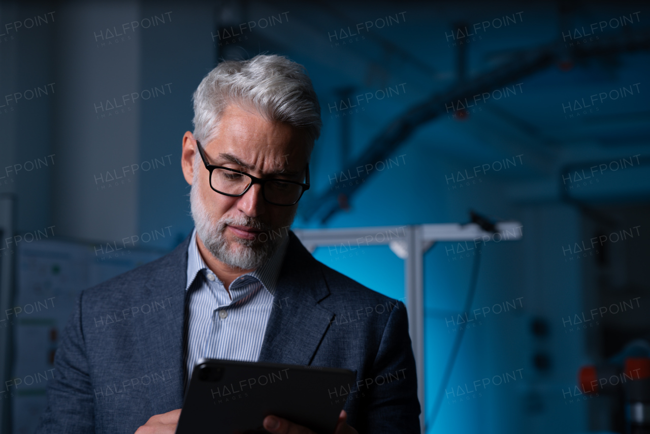 Portrait of robotics engineer holding tablet, standing in laboratory. Concept of modern technology in industries, automated processes, automotive.