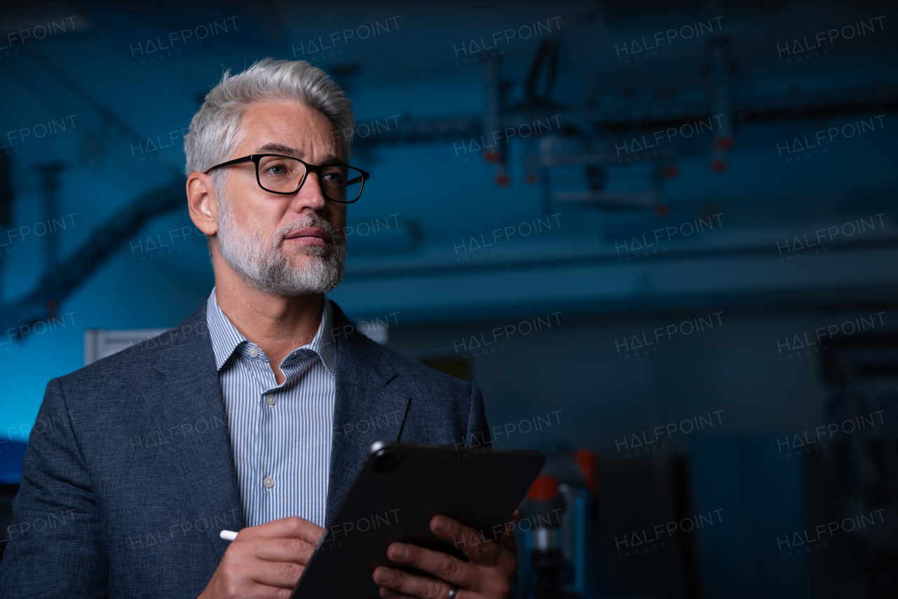 Portrait of robotics engineer holding tablet, standing in laboratory. Concept of modern technology in industries, automated processes, automotive.