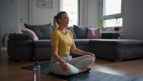 The single woman exercising alone at home, stretching his back and arm. Young woman is happy, relaxed, and content with his life. Solo home workout and meditation, morning or evening workout routine.