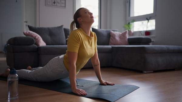 The single woman exercising alone at home, stretching his back and arm. Young woman is happy, relaxed, and content with his life. Solo home workout and meditation, morning or evening workout routine.