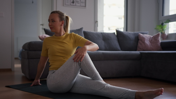 The single woman exercising alone at home, stretching his back and arm. Young woman is happy, relaxed, and content with his life. Solo home workout and meditation, morning or evening workout routine.