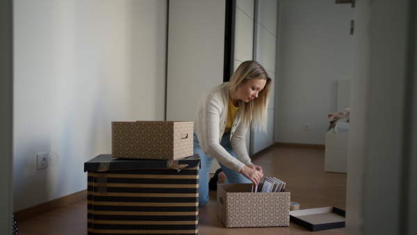 A single woman is assembling furniture in his first own apartment, putting together parts of wooden chair. The young woman living a single life, enjoying his own space.