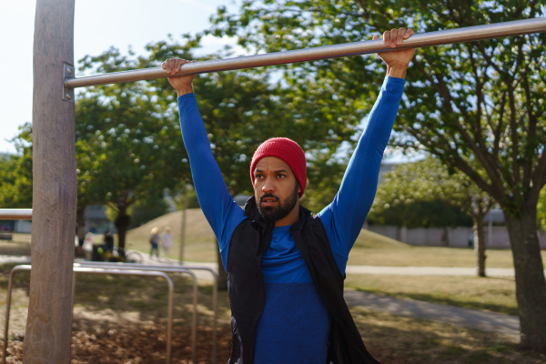 Handsome man exercises outdoors at an urban outdoor gym. Exercising after work for good mental health, physical health, and relieving stress and boost mood. The single man working out alone.