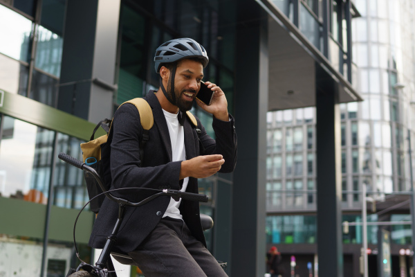 City commuter, businessman phone calling on smartphone while traveling from work to home on bike. City lifestyle of single man.