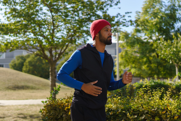 Side view man running outdoors. Exercising after work for good mental health, physical health, and relieving stress and boost mood.