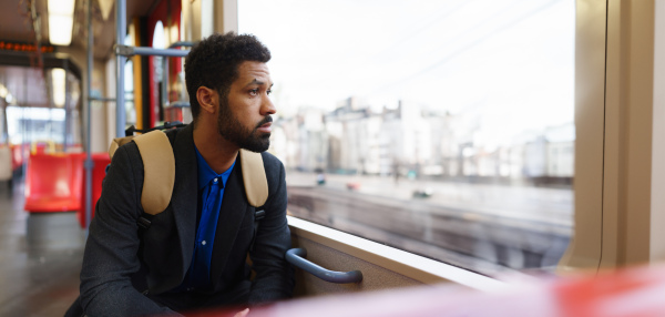 Handsome man traveling by city train, scrolling on a smartphone. Man heading home after a long work day. Single man using dating app.