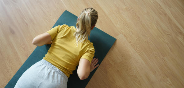 Top view of woman exercising at home, stretching body. Solo home workout and meditation, morning or evening workout routine. Banner with copyspace.