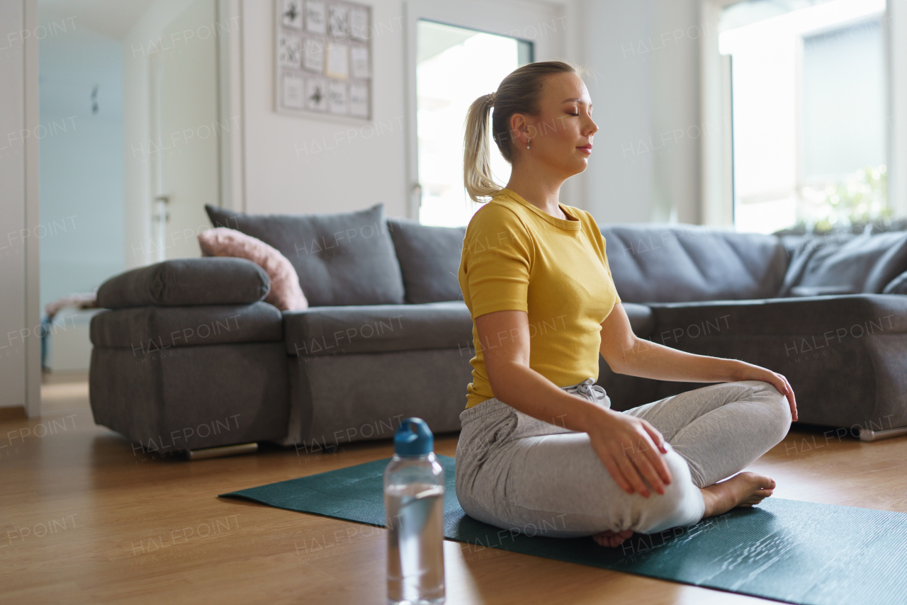 Woman exercising at home, stretching body. Single woman is happy, relaxed, and content with her life. Solo home workout and meditation, morning or evening workout routine.