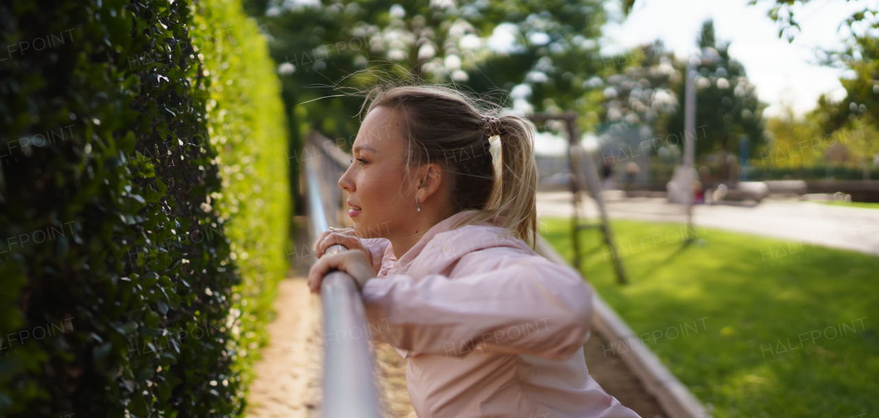 Woman exercises outdoors at an urban outdoor gym, stretching. Exercising after work for good mental health, physical health, and relieving stress and boost mood. Banner with copyspace.