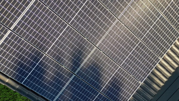 Solar panels on rooftop of modern eco house set in natural environment. Drone shot.