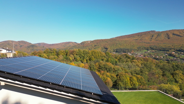 Solar panels on rooftop of modern sustainable home in beautiful nature environtment. Drone shot.