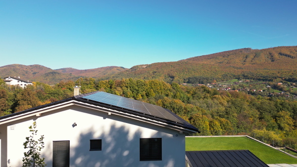 Photovoltaic panels on roof of modern eco house in nature. Drone shot.