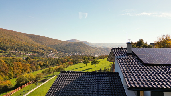 Solar panels on rooftop of modern sustainable home in beautiful nature environtment. Drone shot.