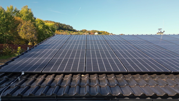 Solar panels on rooftop of modern eco house set in natural environment. Drone shot.